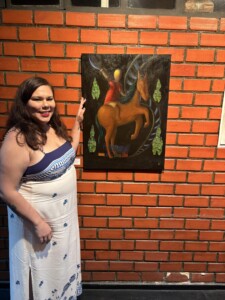Eu com meu quadro "O erê Jorginho e seu pocotó" na exposição coletiva "Fios invisíveis", no Centro de Artes Calouste Gulbenkian Eu de vestido colocando a mão no meu quadro "O erê Jorginho e seu pocotó" na exposição coletiva "Fios invisíveis", no Centro de Artes Calouste Gulbenkian