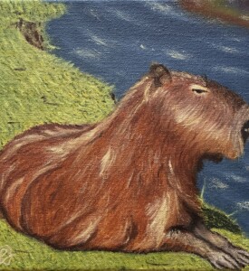 Capivara deitada em uma grama ao lado de um rio